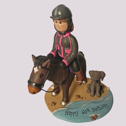 Clay birthday cake topper of person on horse with dog